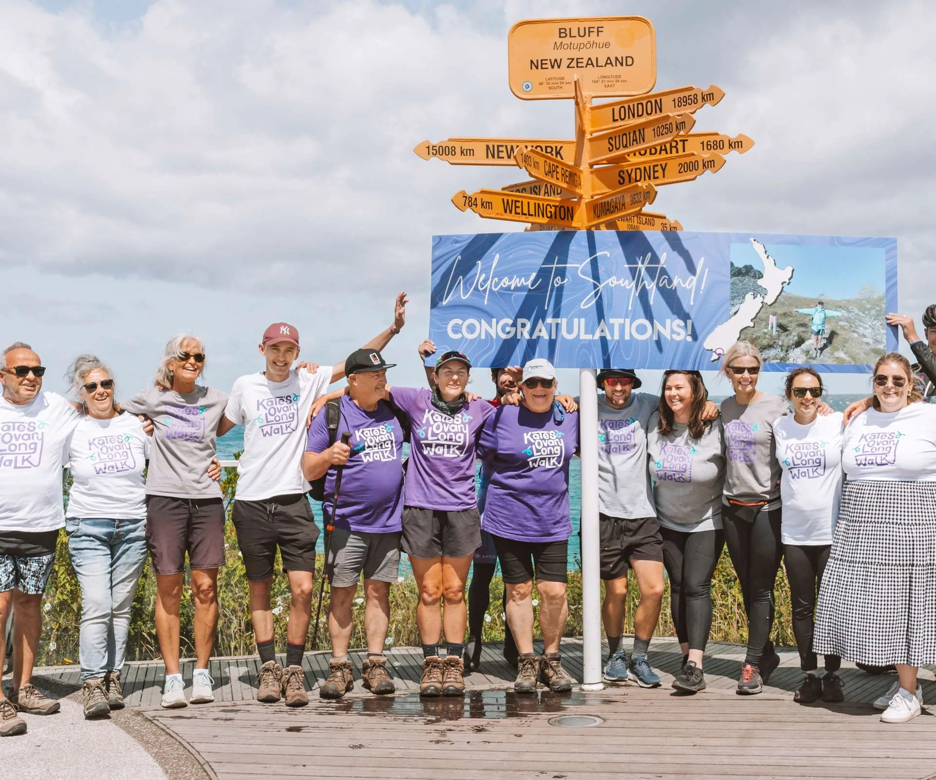 Kate standing at the bottom on New Zealand surrounded by her family and friends