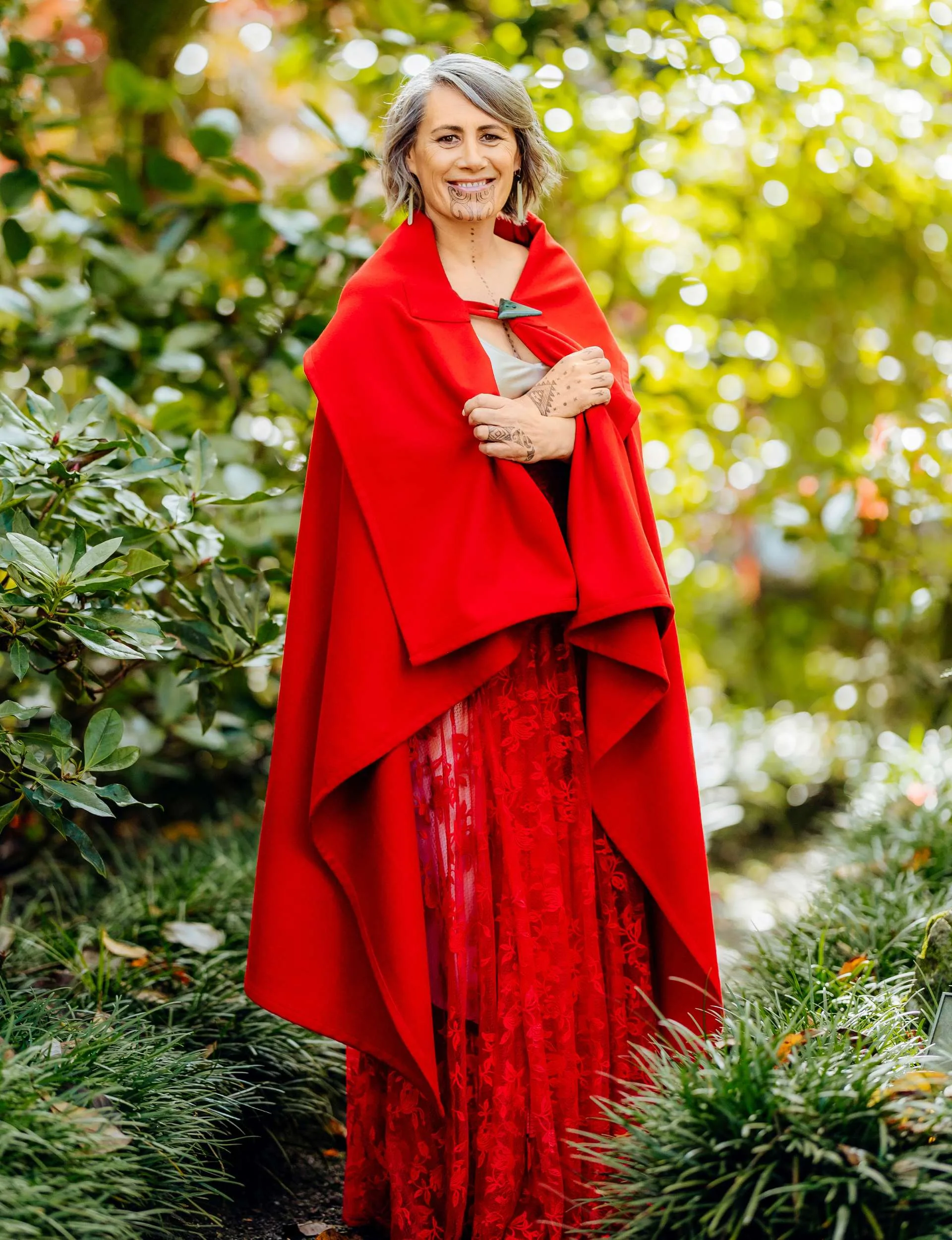 Jenny-May standing amongst bushes wrapped in a long red cloak