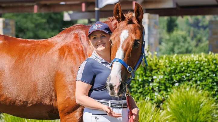 Louise standing in front of her horse, with his head wrapped over her shoulder