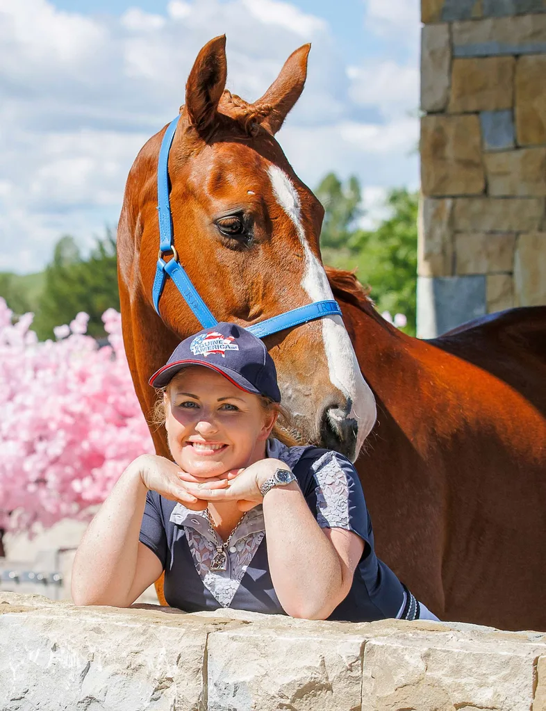 Louise leaning on the top of a low wall in front of her horse