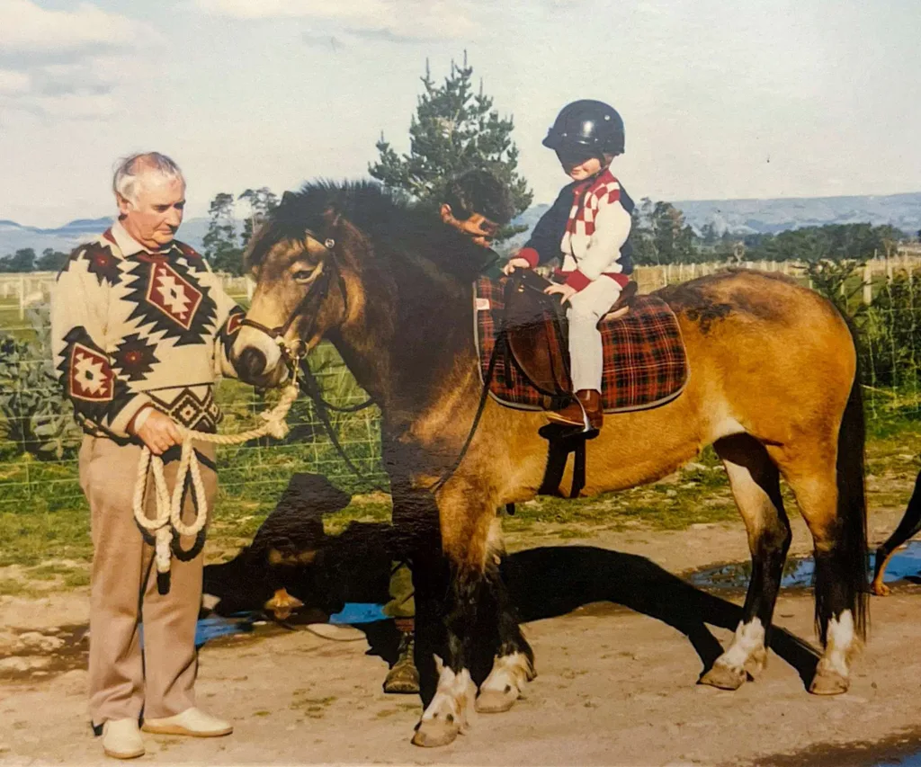 Louise riding a horse as a child, with her grandfather holding the reins