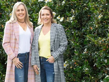 Jackie and Becki standing in front of a hedge