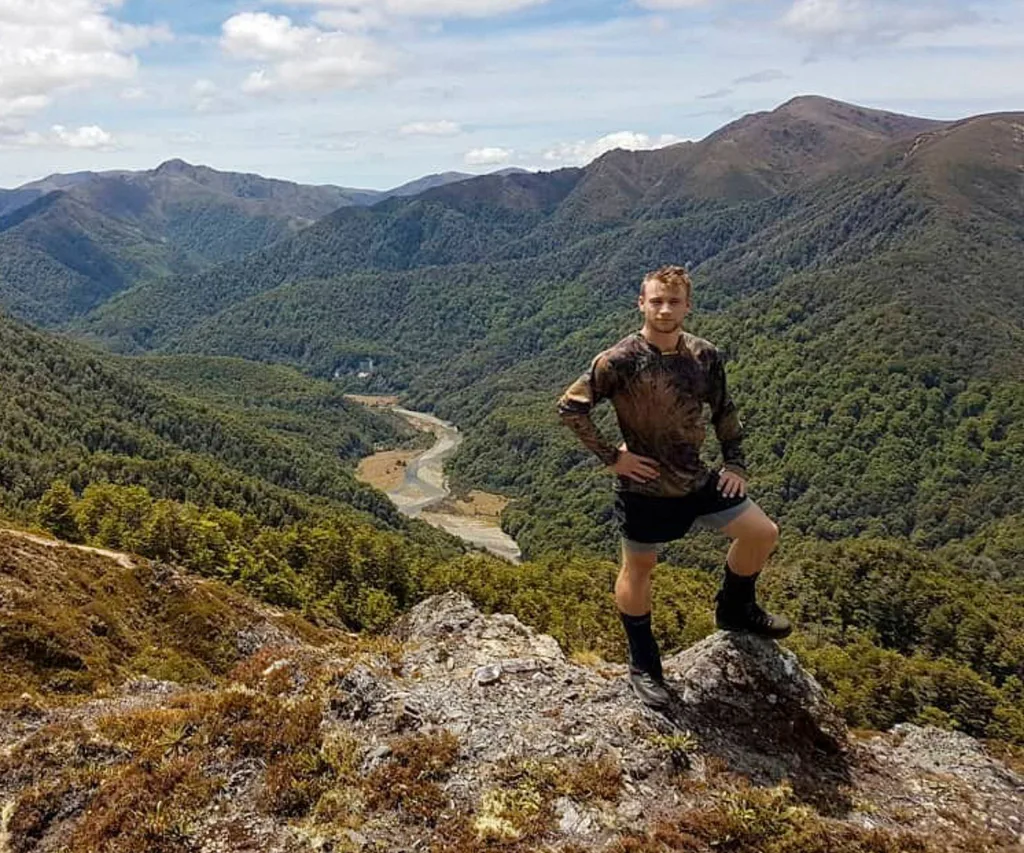 Dylan Schmidt ion top of a mountain in hunting gear