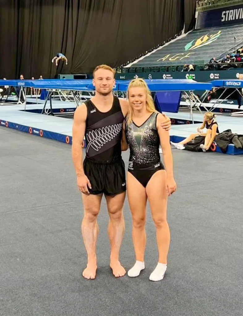 Maddie and Dylan in their competing uniforms in front of trampolines