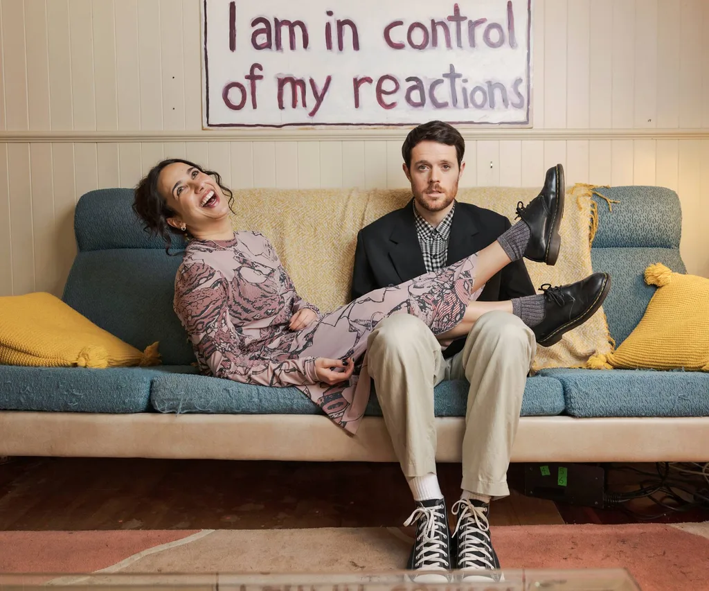 Paul sitting on a couch with Simone next o him, her legs over his