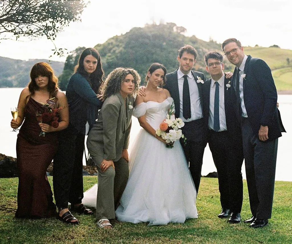 Simone and Guy at their second of two weddings, with their bridal party around them in front of a lake