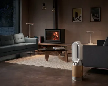 Modern living room with a fireplace, sofas, and a Dyson air purifier on the floor.