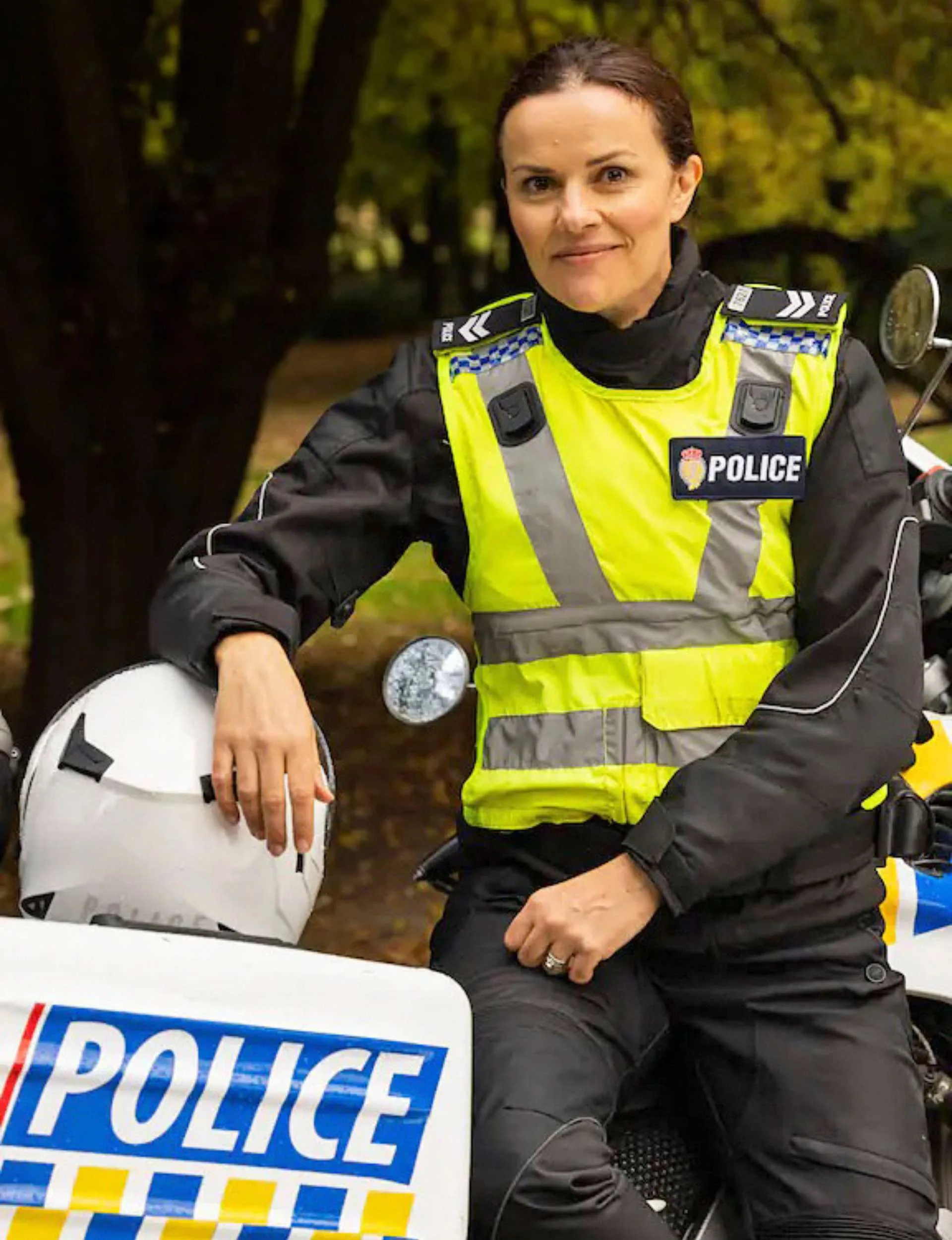 Amanda in a police costume, leaning on a police motorbike on set of Under The Vines
