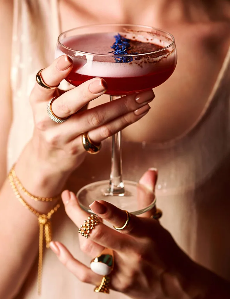 Close up of woman's hands holding a cocktail in a glass