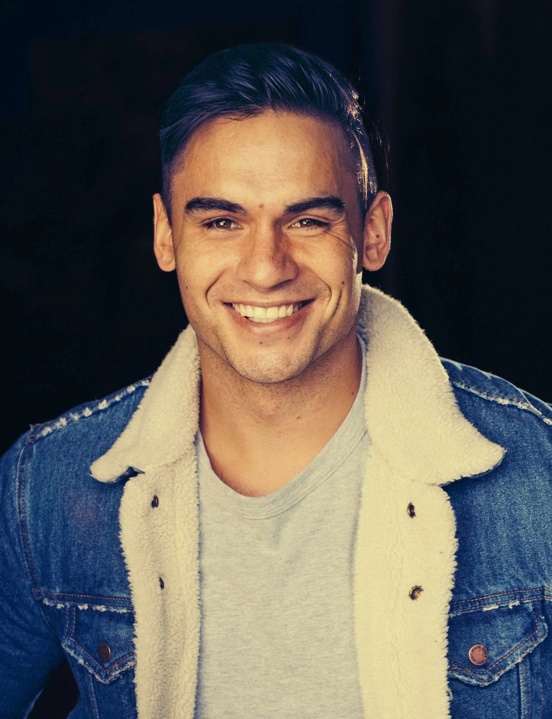 Teone Kahu in a denim jacket in front of a black background
