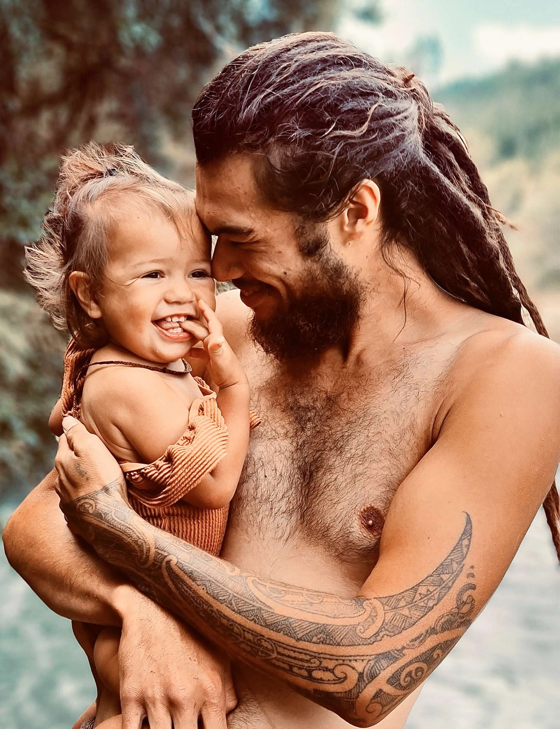 Jasmine’s husband Pineamine holding their daughter while standing in a river