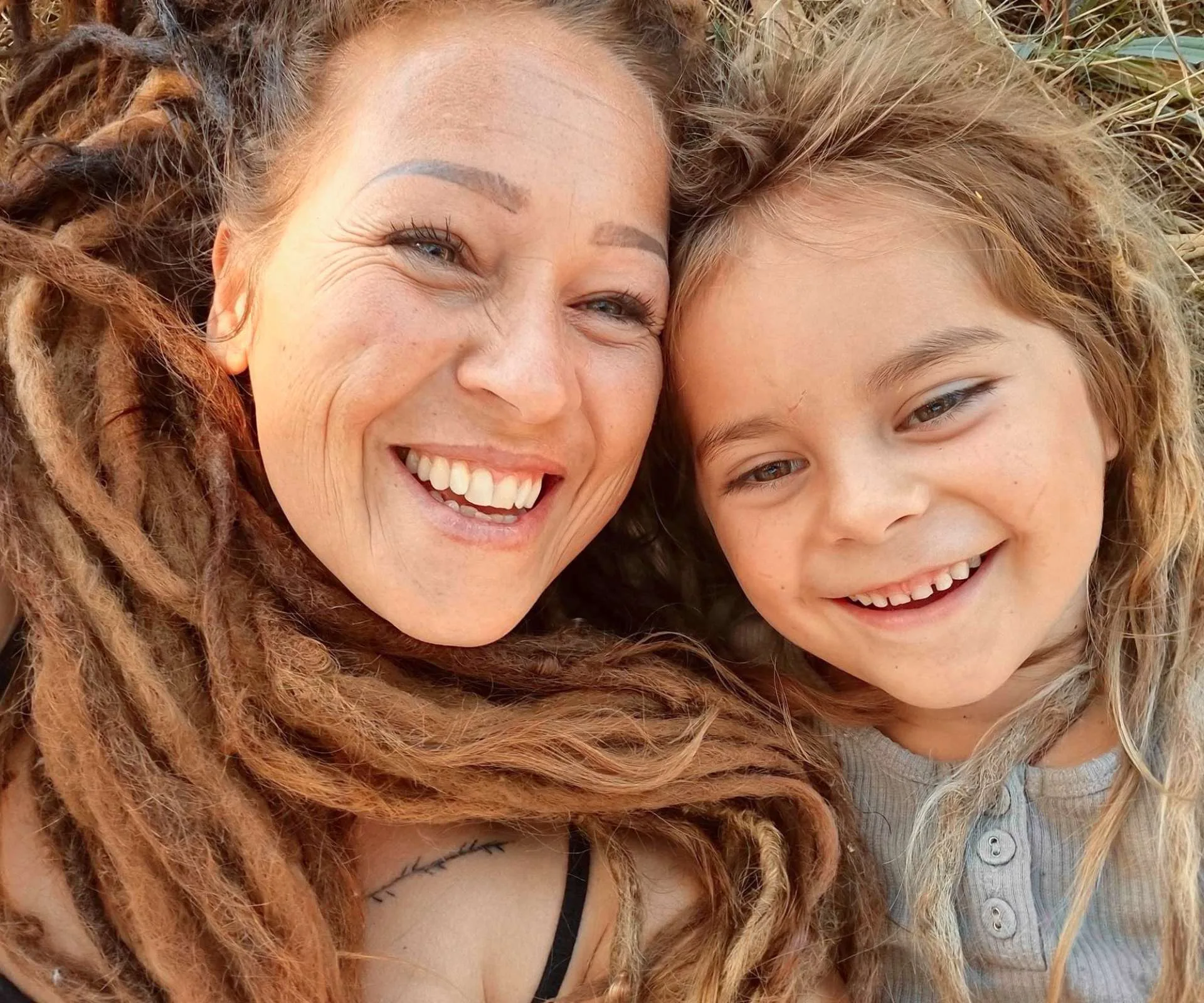 Jasmine’s mother Keri and younger brother both laying on the grass with their dreadlocks surrounding their faces