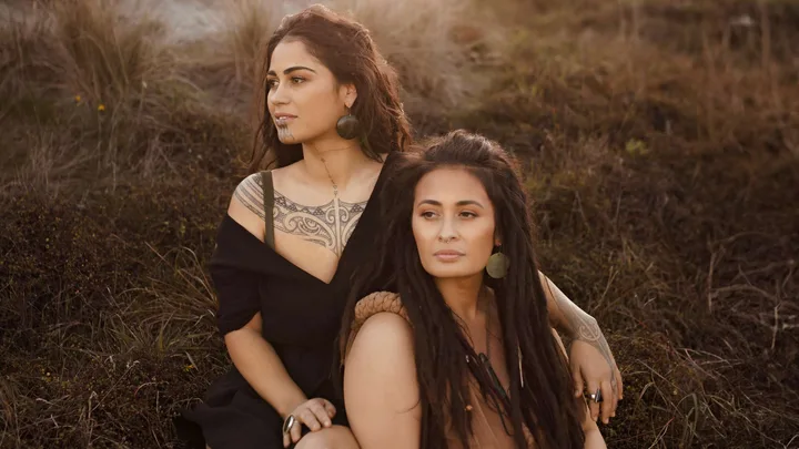 Jasmine and Wikitoria sitting on a grassy hill