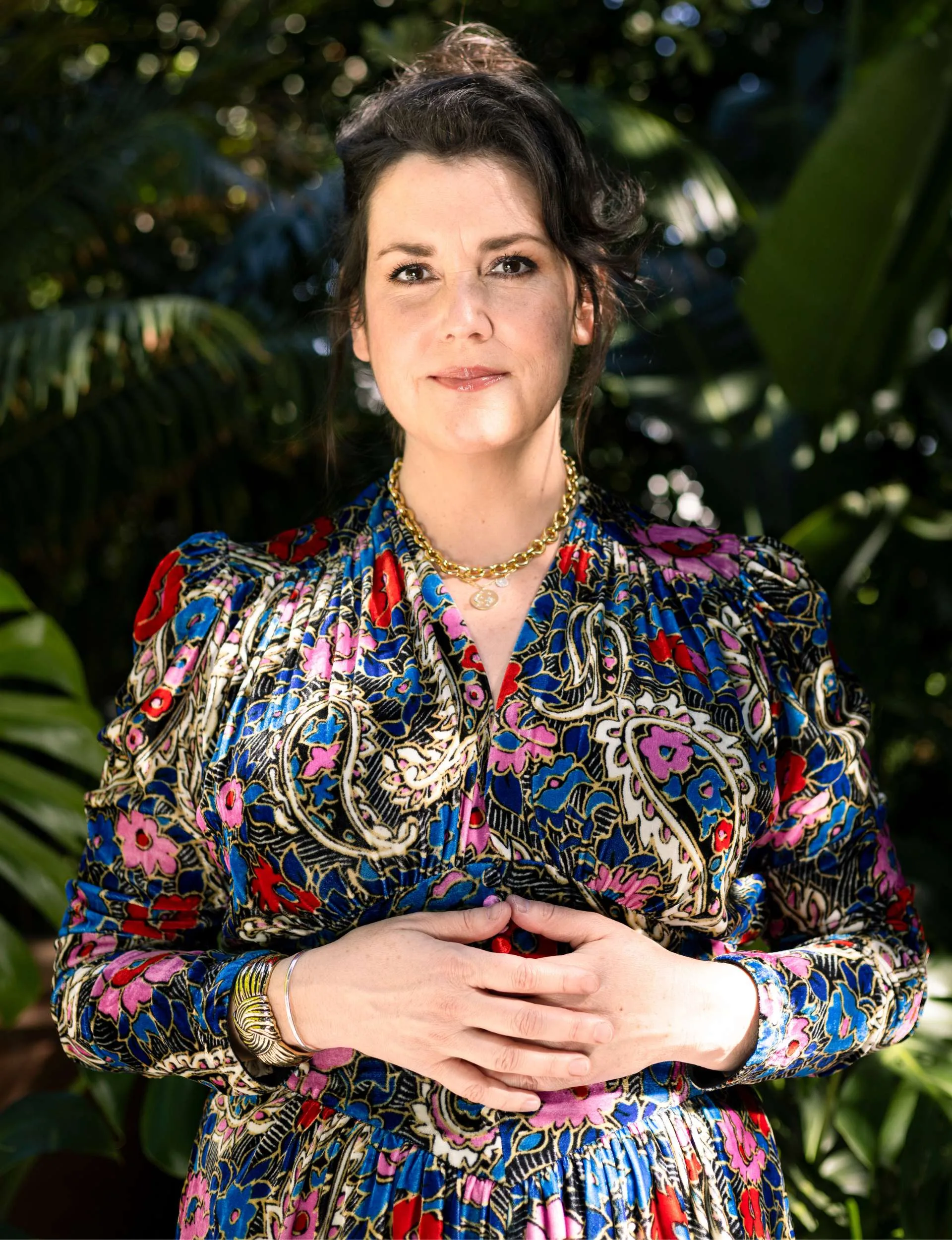 Melanie with her hands relaxed over her sternum, smiling