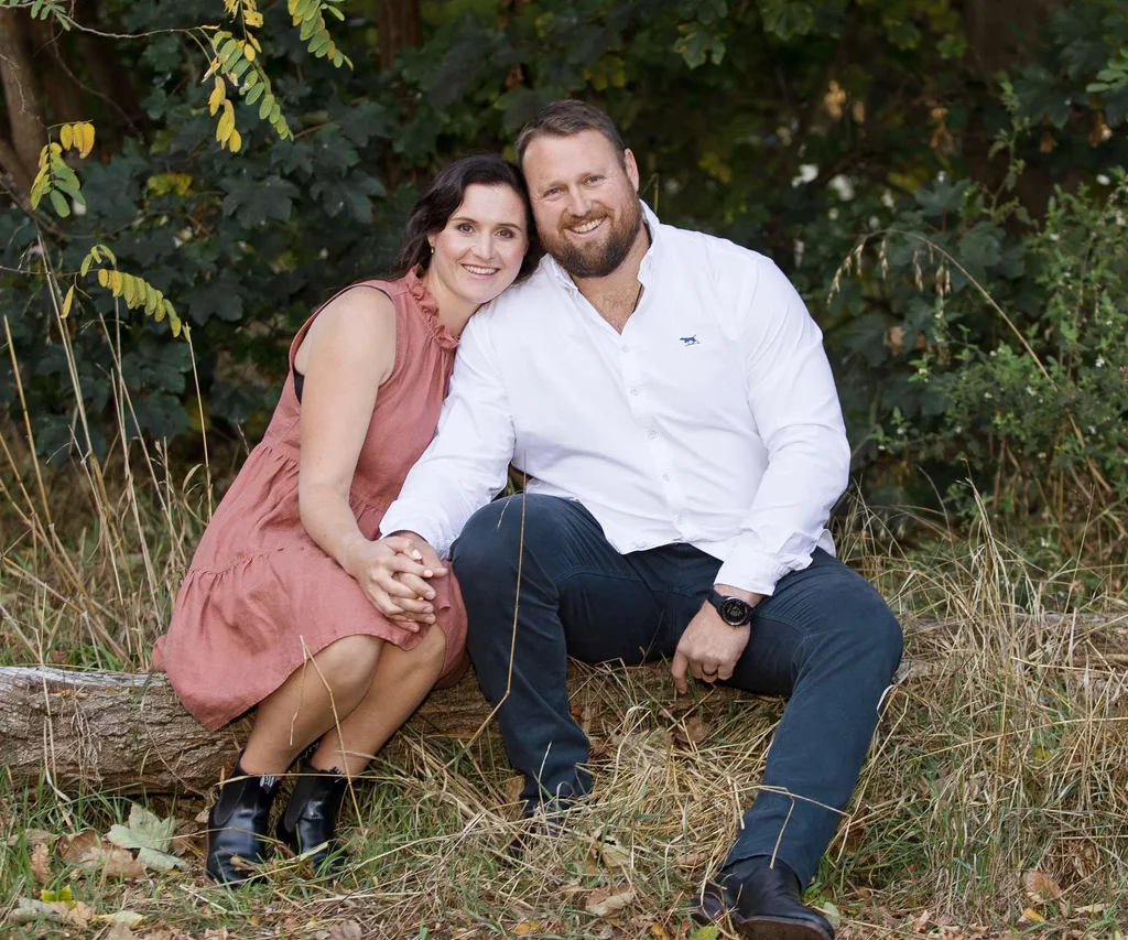 Tom and Dana sitting on a log holding hands