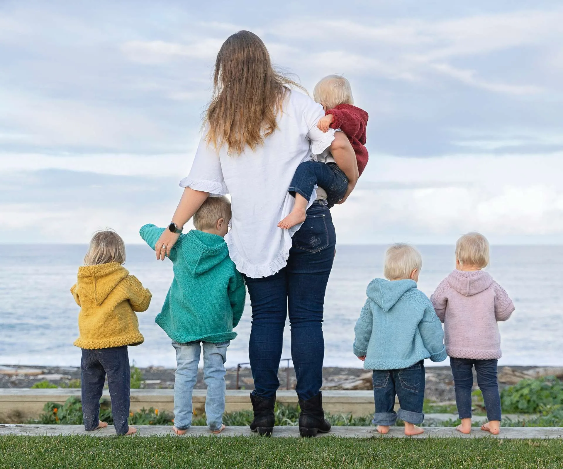 Joanne and her five kids standing with their backs to the camera, looking out to the beach