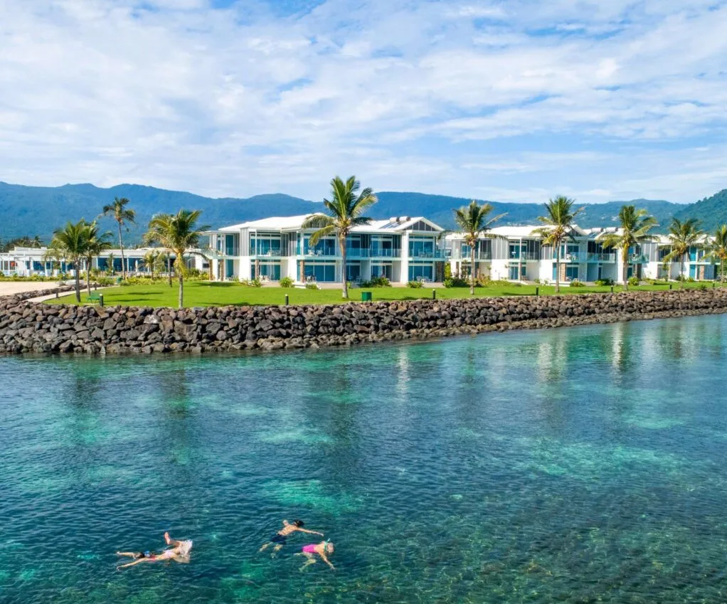 Taumeasina Island Resort with three people swimming in the sea in front