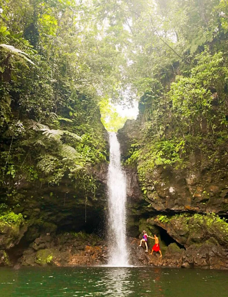 A couple climbing up under the Afu Aau Waterfall.