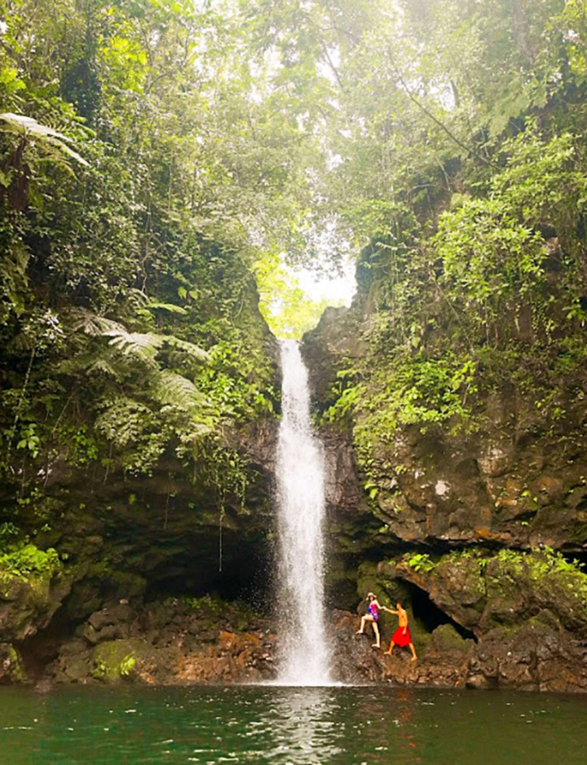 A couple climbing up under the Afu Aau Waterfall.