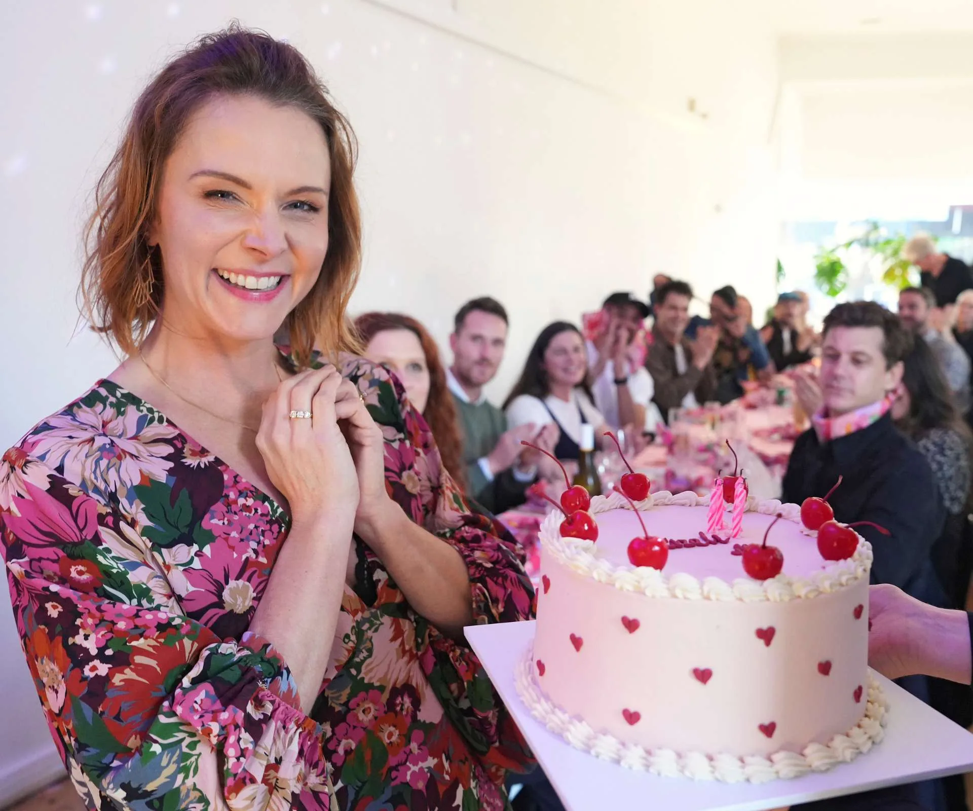 Ria Vandervis standing excitedly beside her cake
