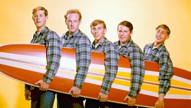 The Beach Boys holding a surfboard