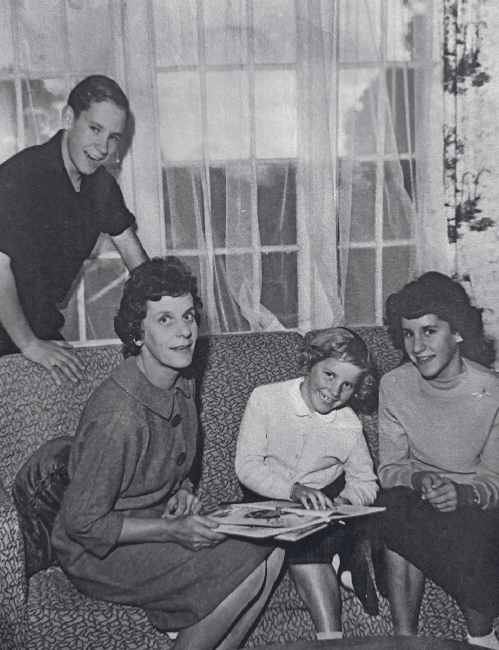 A black-and-white photo of a family sitting on a couch in their living room