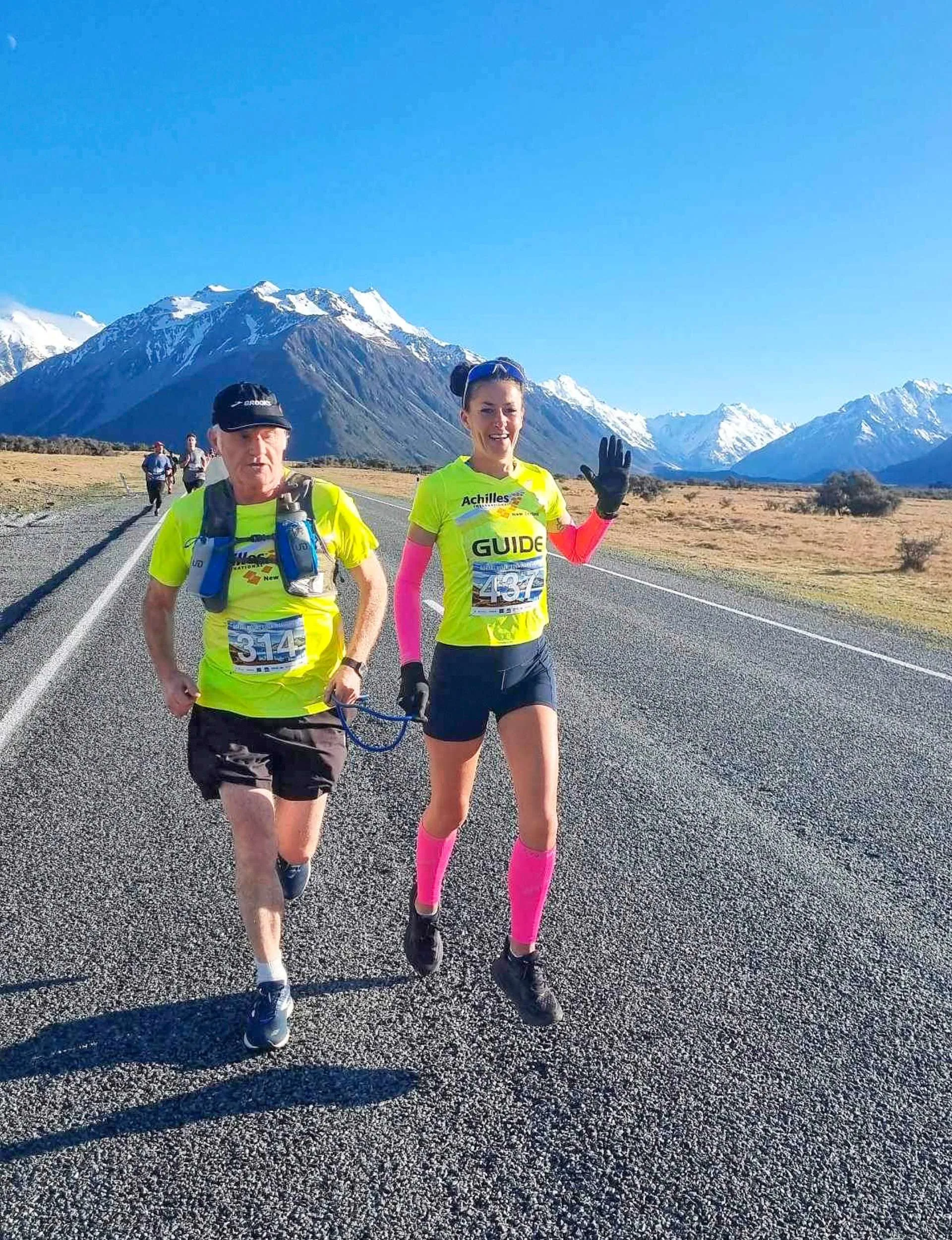 Paul and Rosie running down a road with large snowy mountains in the background