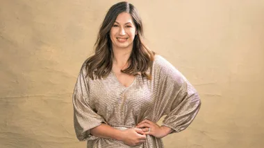 Emma-Kate Woodham in front of a gold background, wearing a gold dress