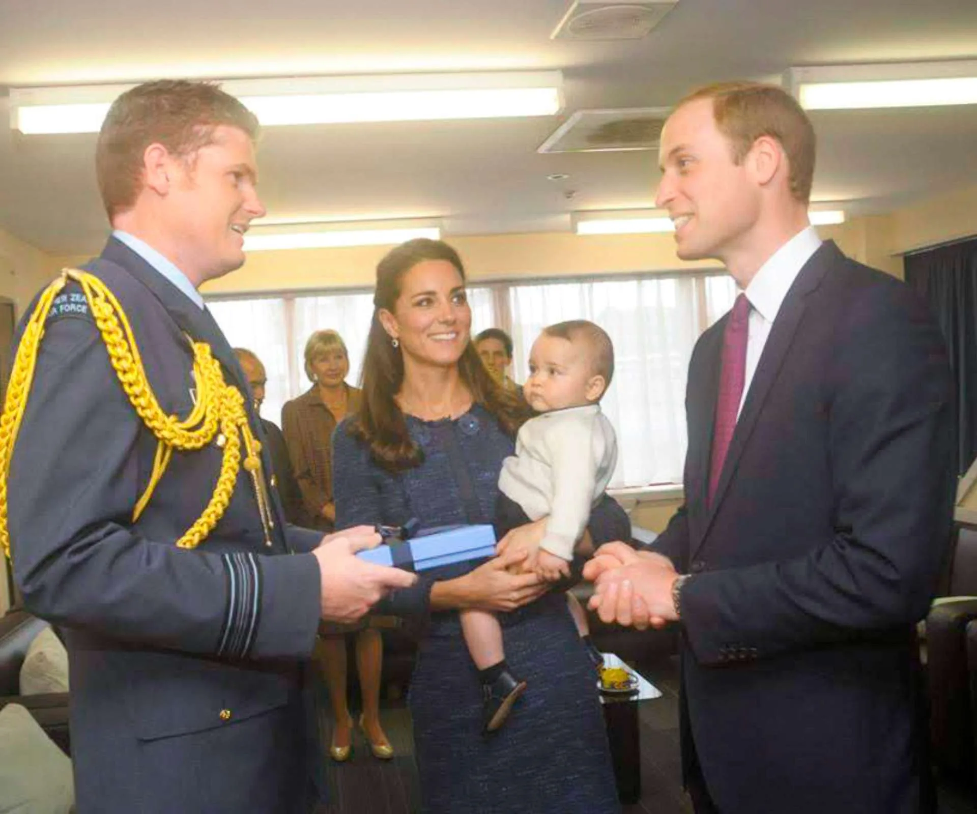 Tim Costley receiving an award from William and Kate, while Kate holds a baby George.