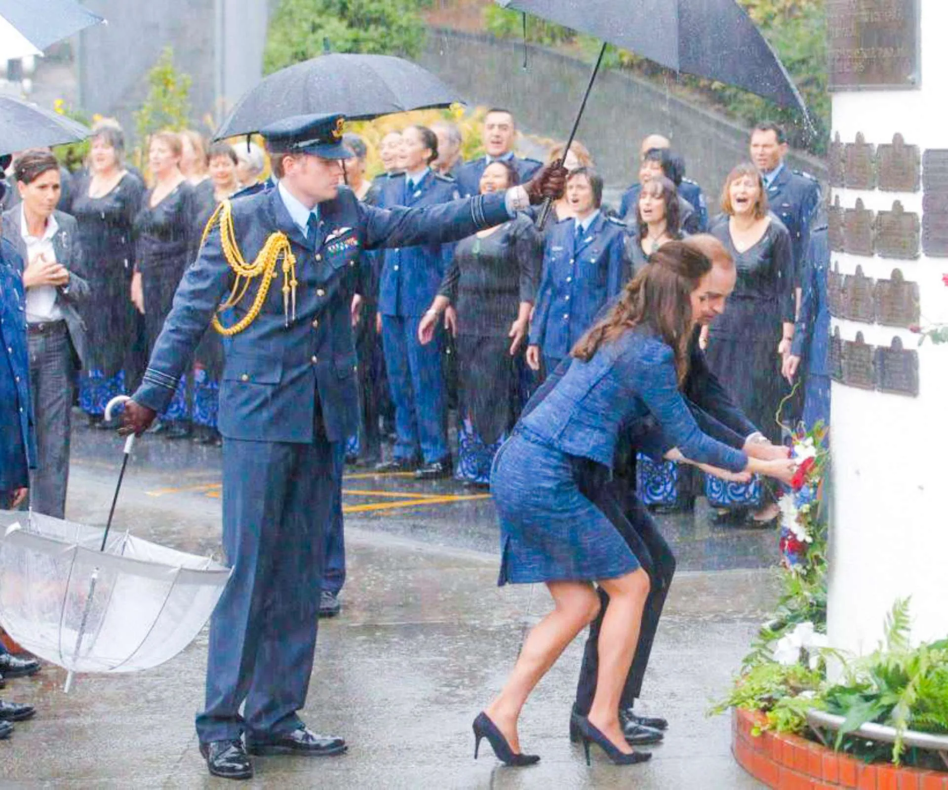 Tim holding an umbrella over Wills and Kate at a memorial
