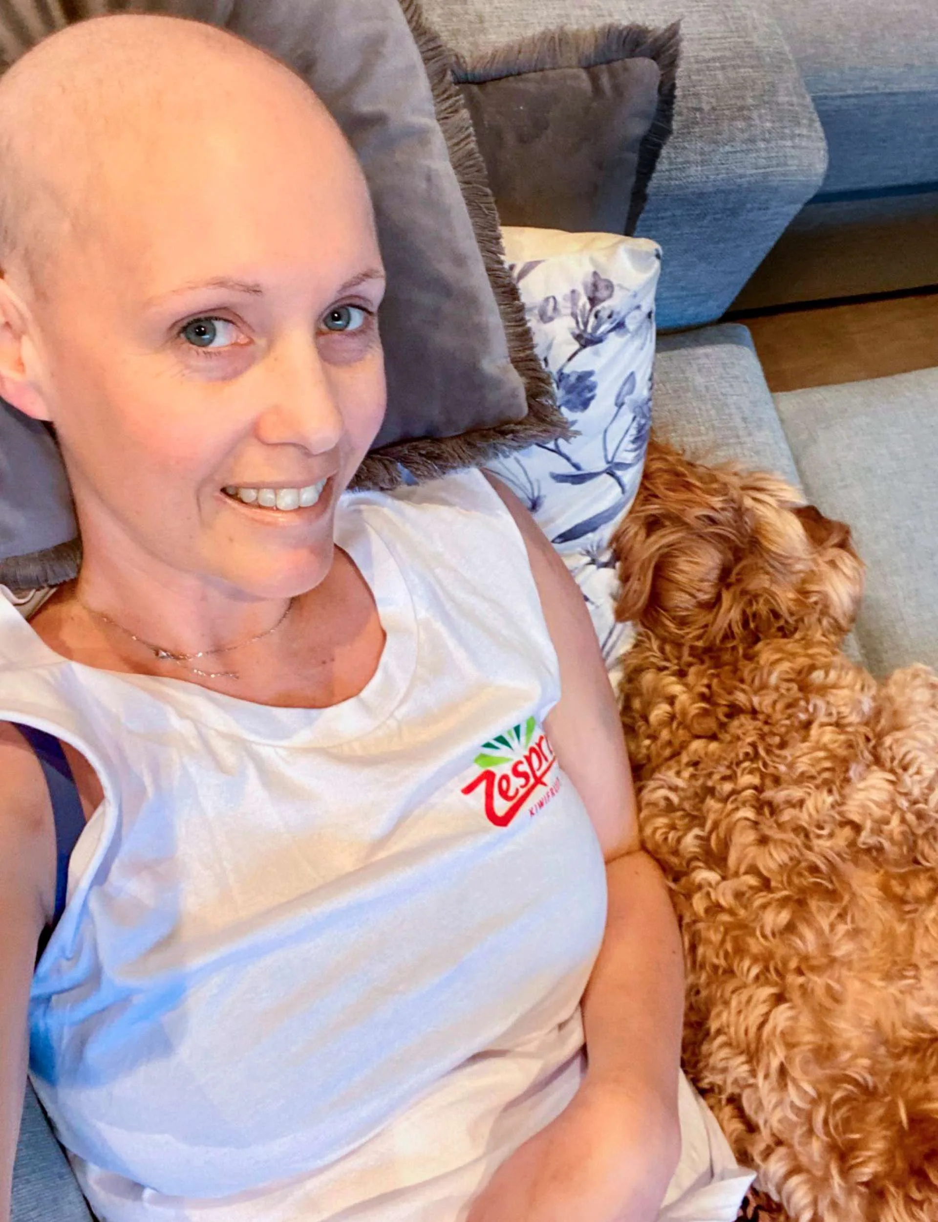 Celia laying next to her dog with a shaved head