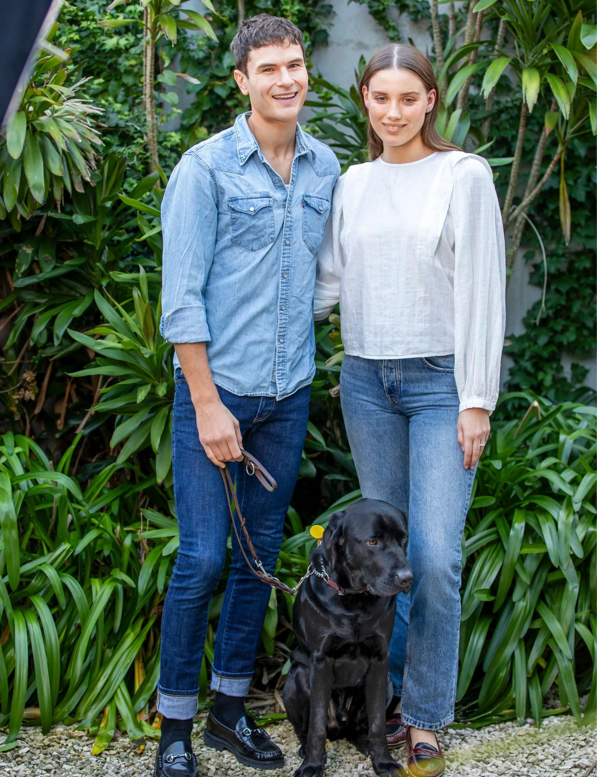 Michael with his partner and guide dog in front of a bush