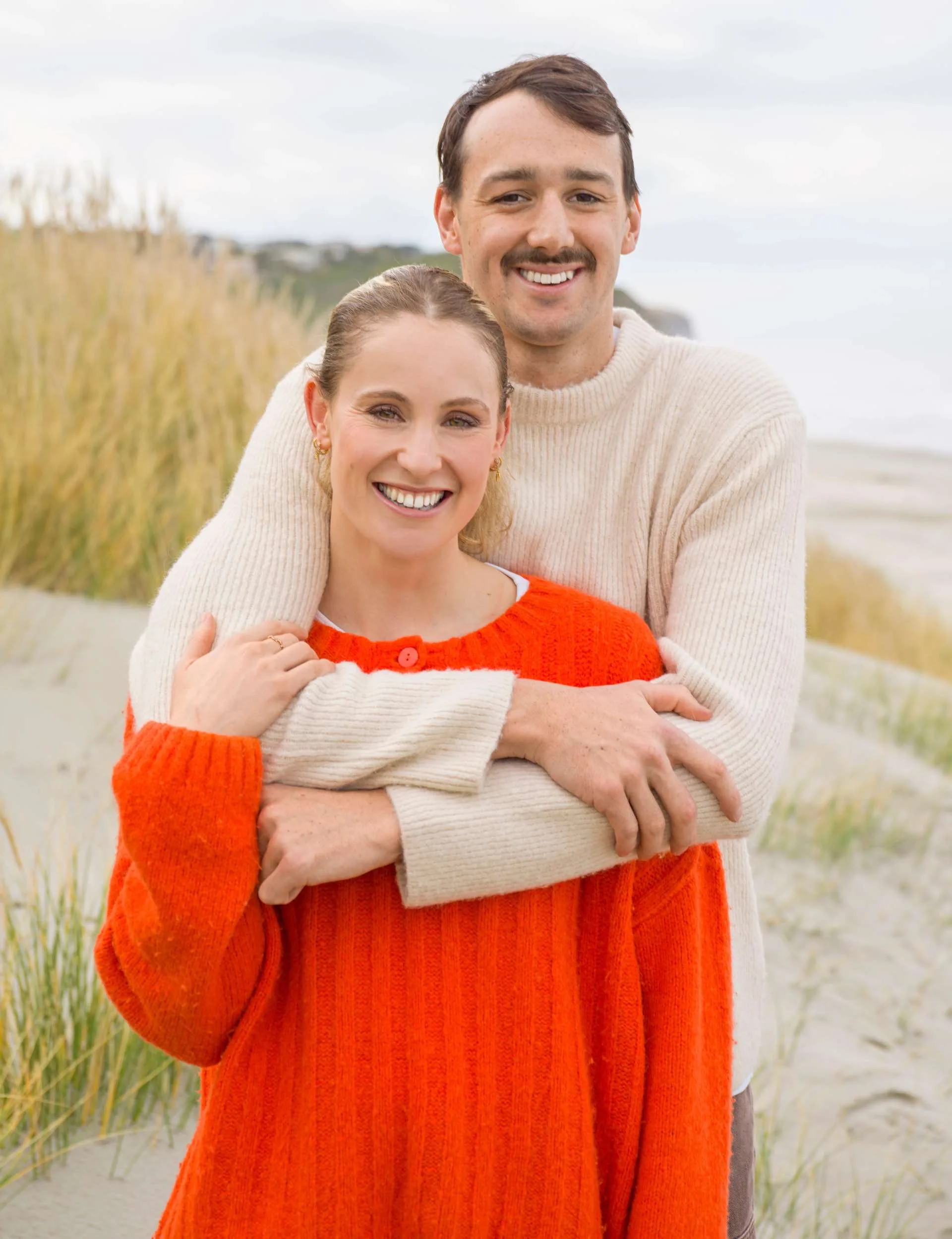 Kane standing behind Caitlin with his arms over her shoulders