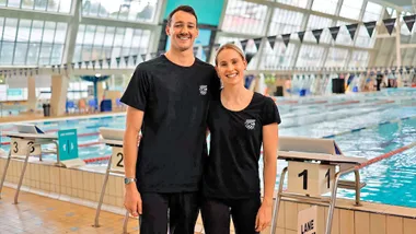Kane and Caitlin in front of a pool in their Team New Zealand gear