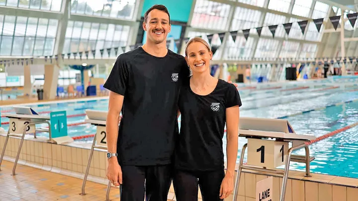 Kane and Caitlin in front of a pool in their Team New Zealand gear