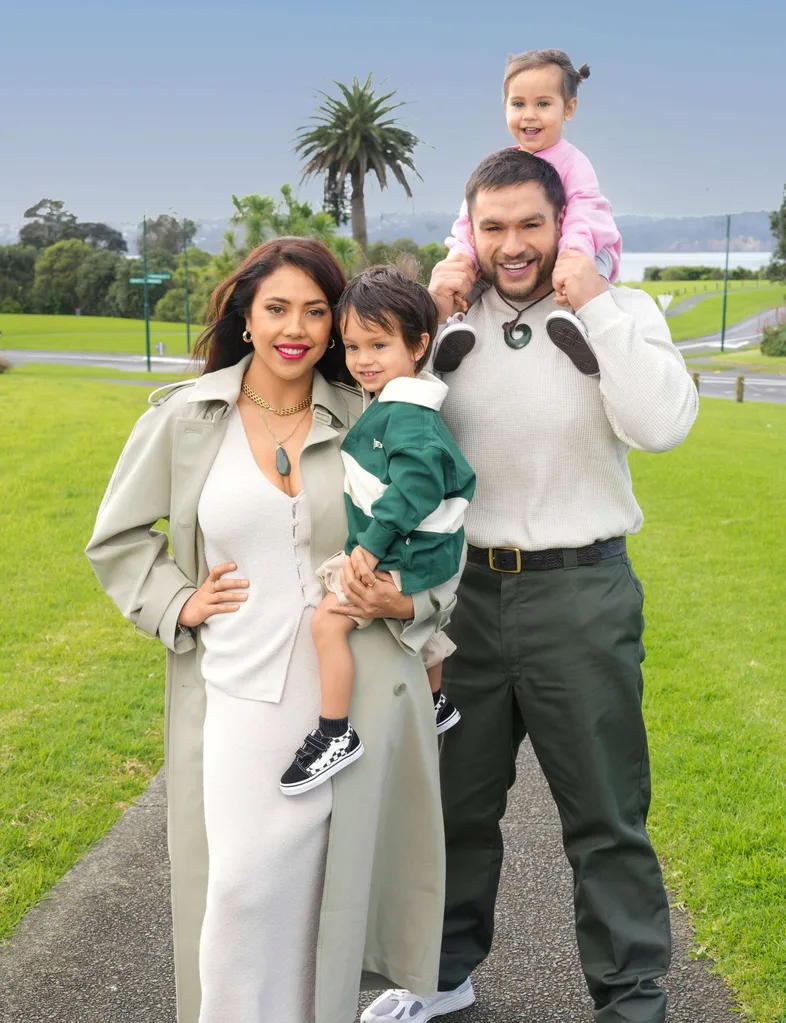 Teone carrying Awea on his shoulders while Ngahuia holds Niau on her hip