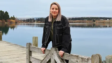 Whitney Greene leaning on a wooden fence on a wharf