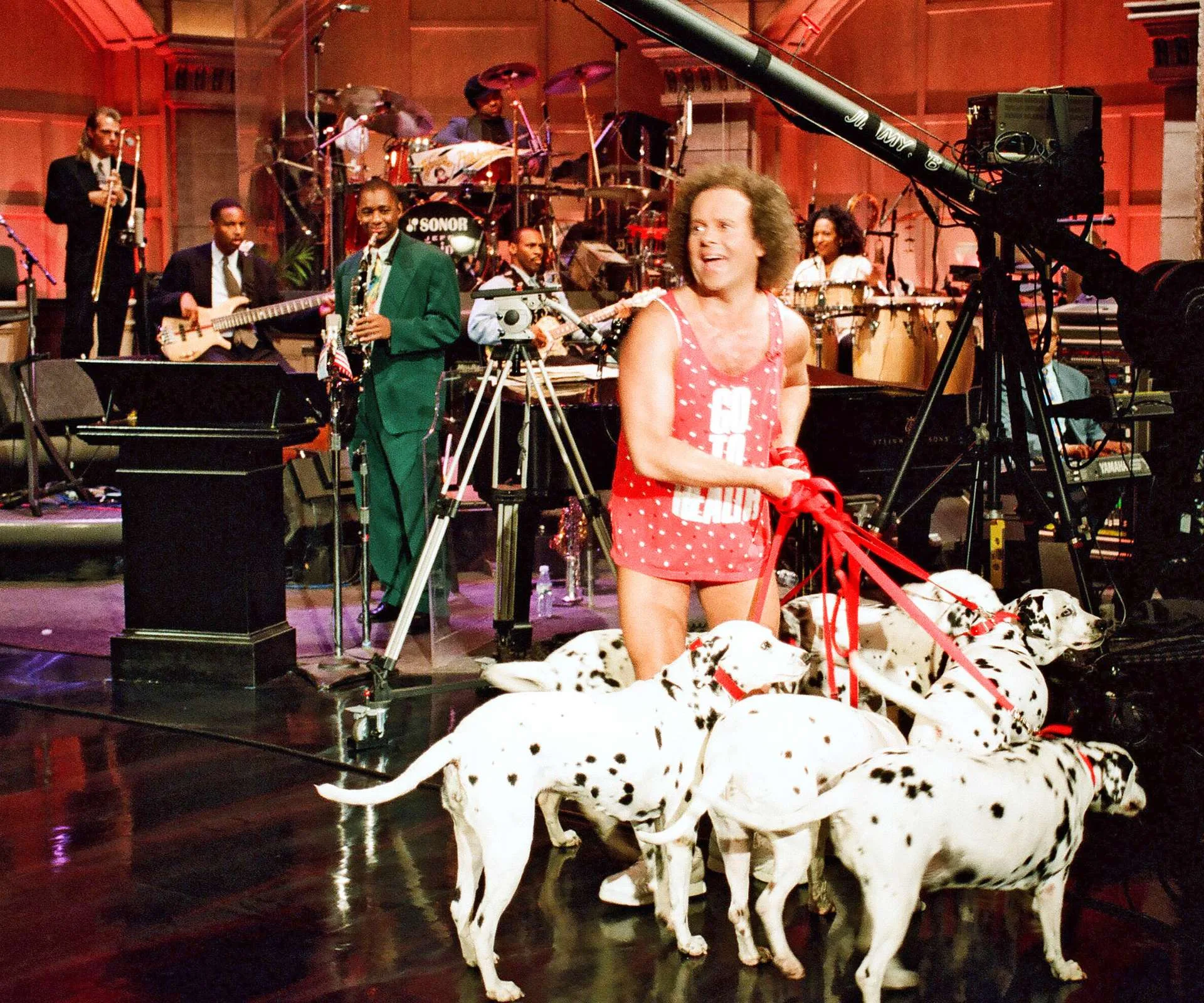 Holding six Dalmatian dogs in front of a band on the stage of a show