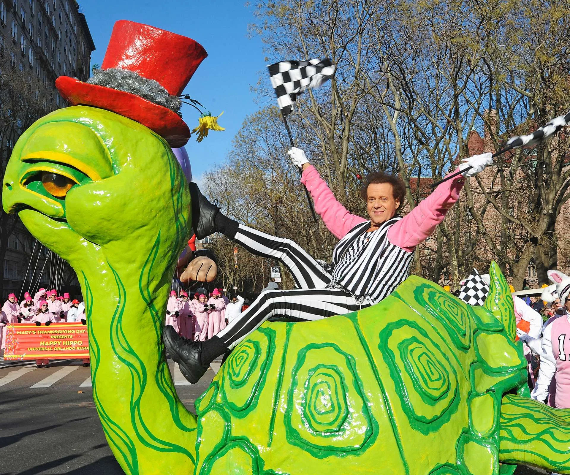 Richard Simmons sitting on the back of a giant plastic turtle