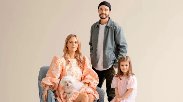 Traitors star Mike standing behind his family who are sitting in front if a gold backdrop