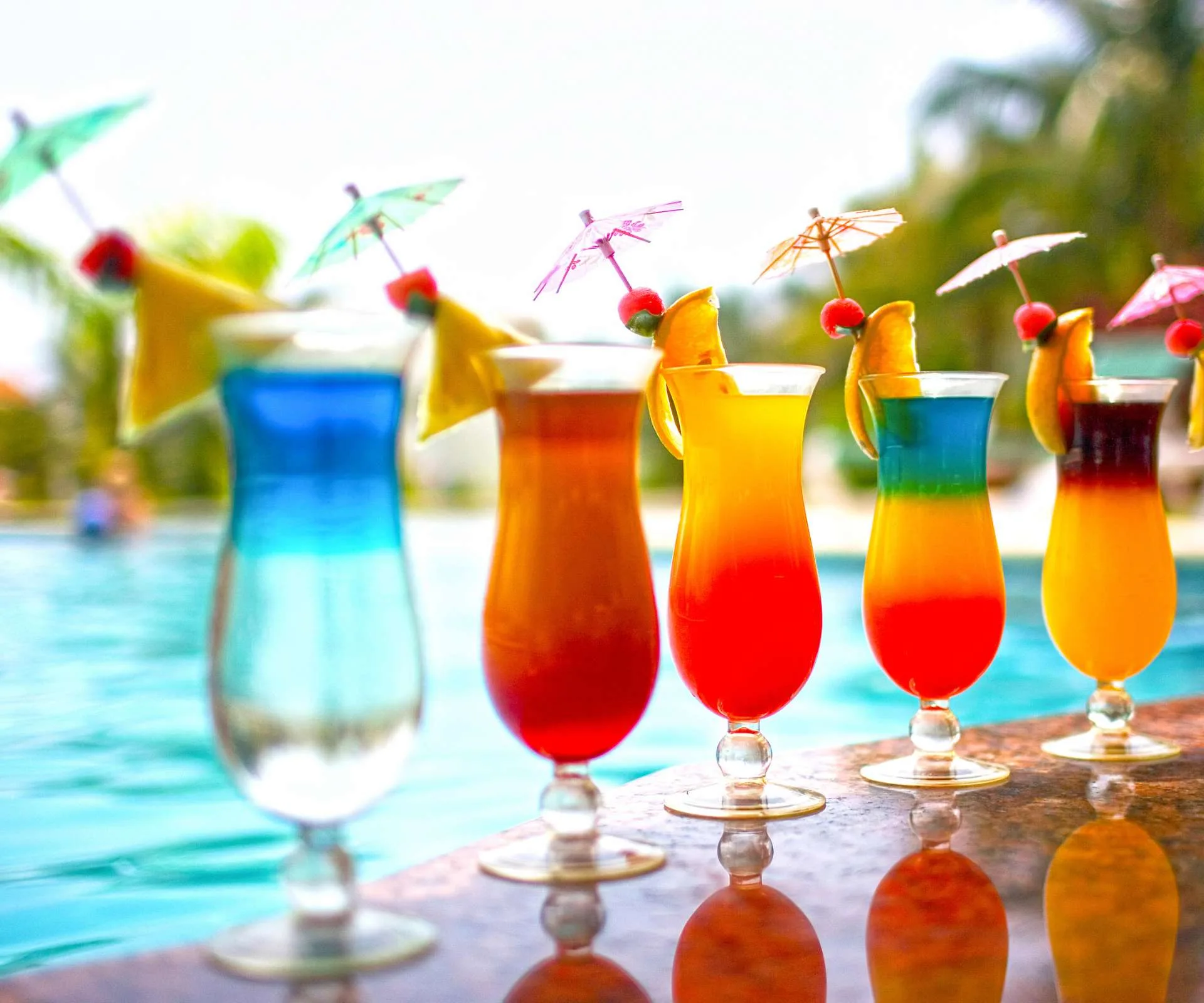 Cocktails lined up beside a pool