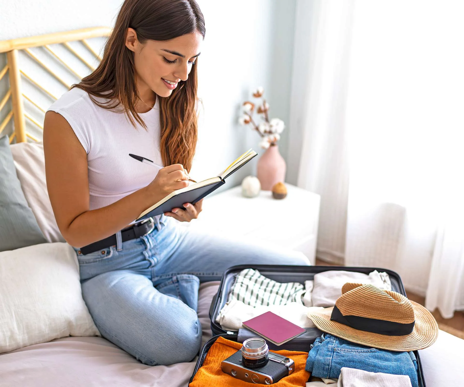 Woman ticking off her packing checklist against the packed bag in front of her