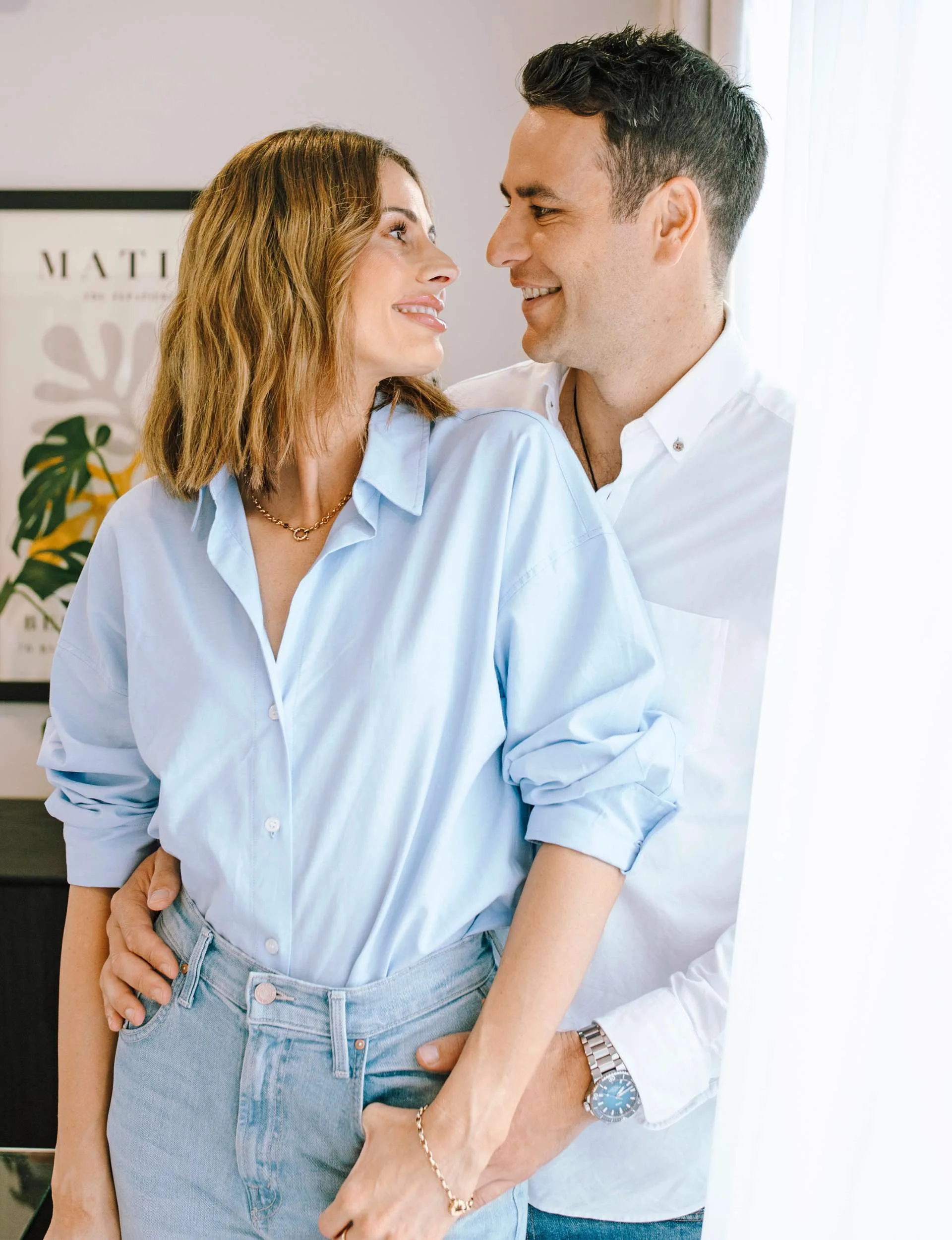 Smiling at each other while standing amongst some airy white curtains