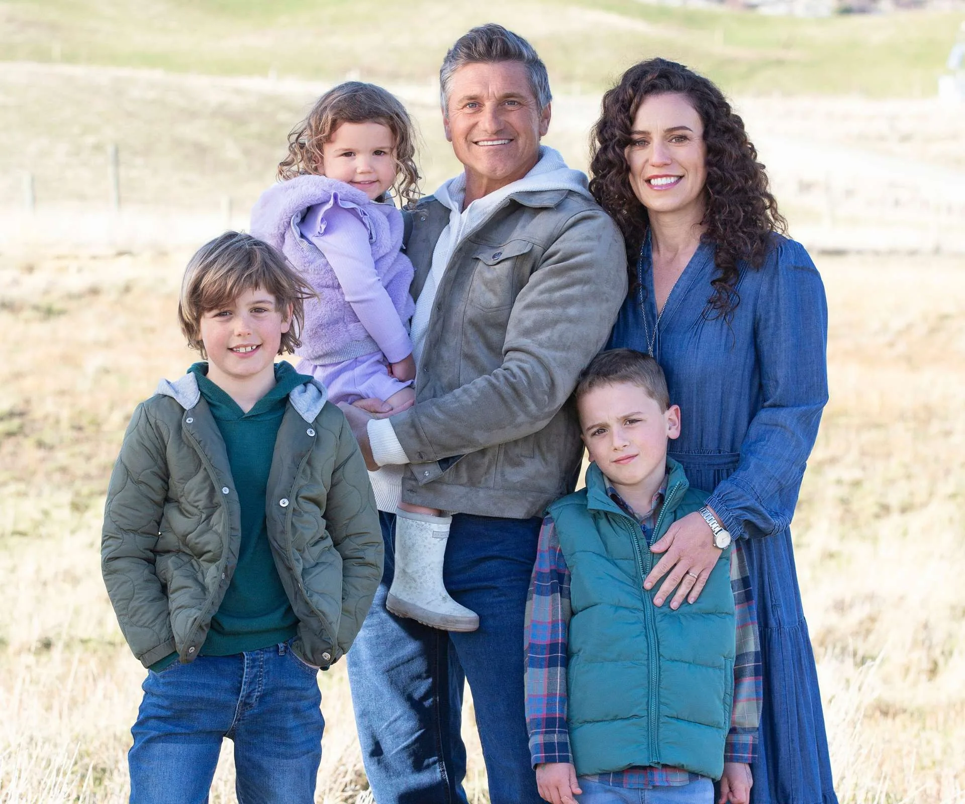 Matt Chisholm standing in a paddock on the farm with wife Ellen and their kids
