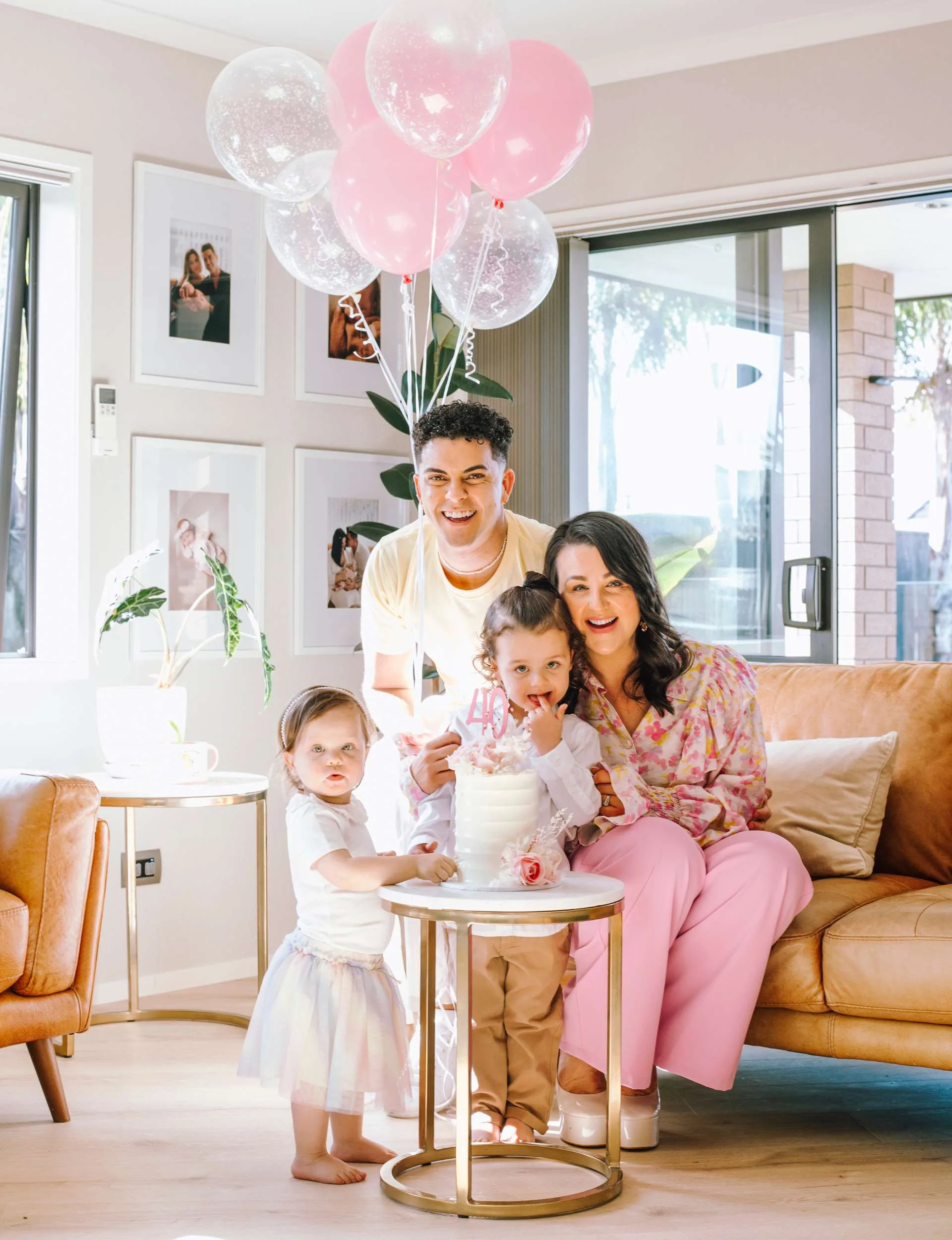 The family smiling with the birthday cake and balloons