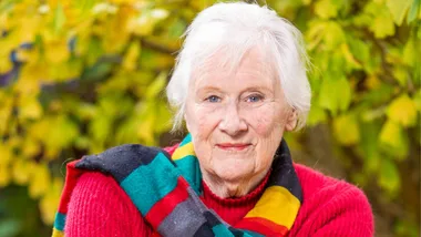 Tessa Duder smiling with a colourful striped scarf around her neck