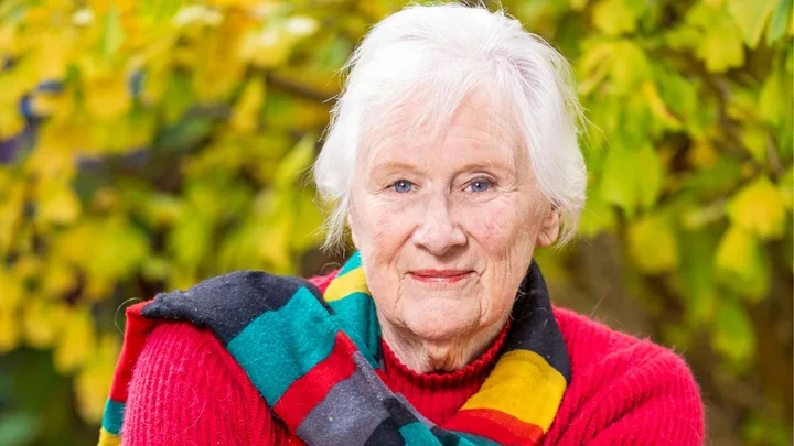 Tessa Duder smiling with a colourful striped scarf around her neck