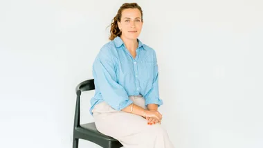 Devon sitting on a black stool in front of a white wall