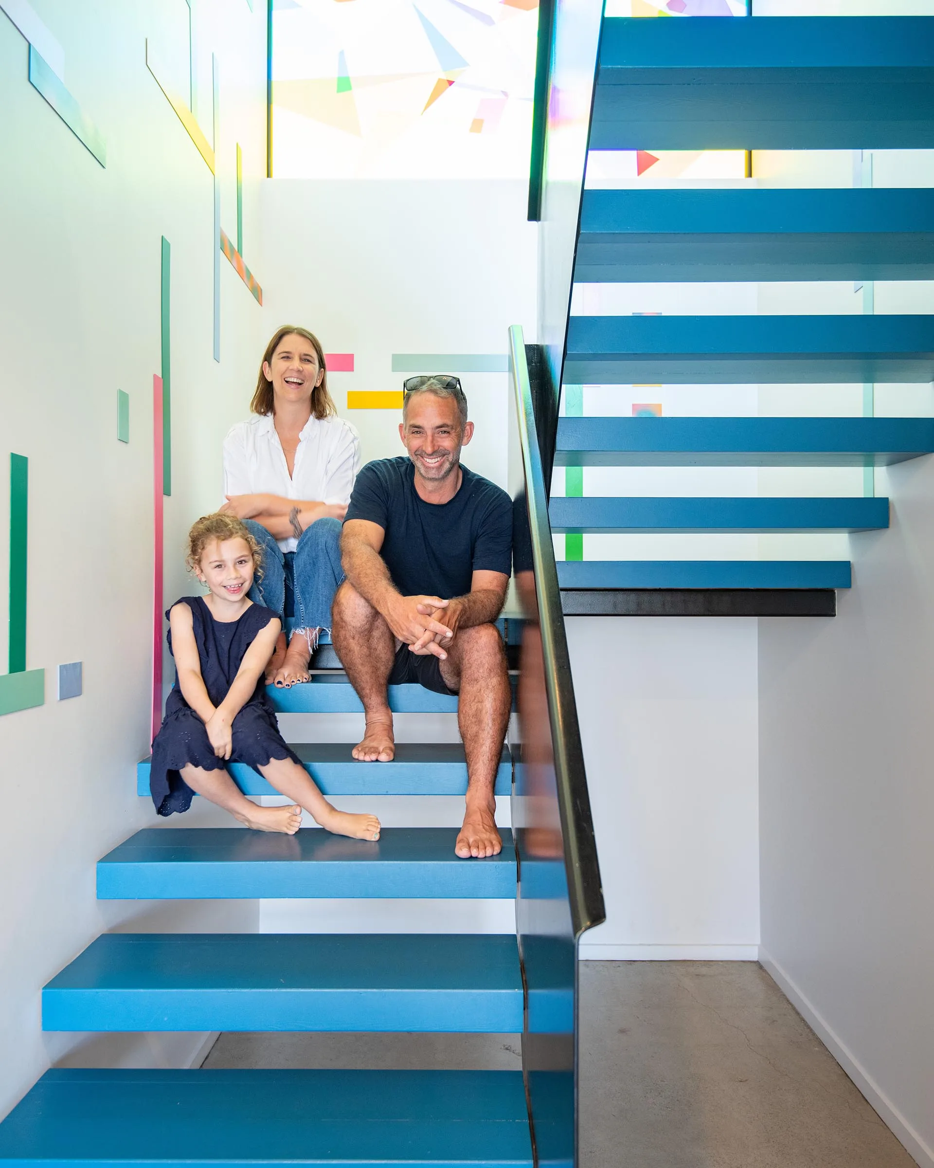 Family sitting on the floating staircase painted in Resene Spinnaker and balustrade in Resene Foundry