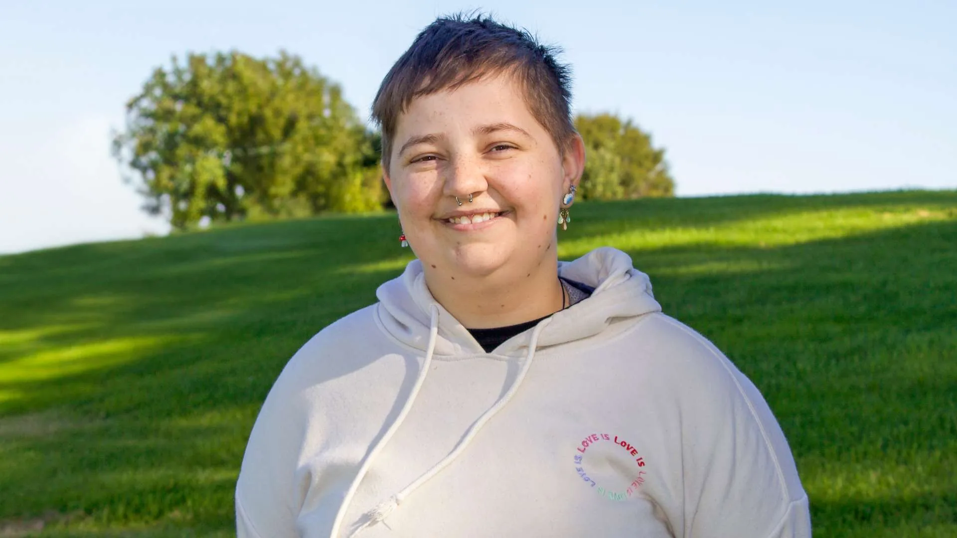 Finn Everall smiling in front of a grassy hill